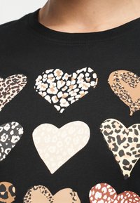 Μαύρο ύφασμα με έξι καρδιές σε διάφορα μοτίβα λεοπάρ και αποχρώσεις μπεζ, καφέ και μαύρου, διατεταγμένες σε δύο σειρές.