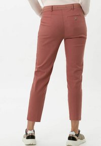 Tailored pants in a rose color, made from soft fabric. Features a back pocket with a button, slim fit, and ankle-length cut.