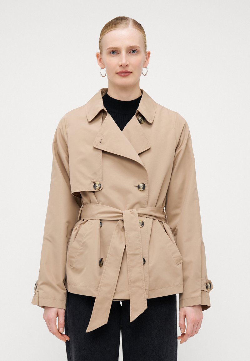 Trench coat beige doppiopetto con cintura, tasche laterali, colletto ampio e polsini con bottoni; realizzato in tessuto liscio e leggero.