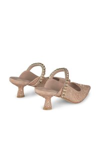 Mule con tacco rosa con upper testurizzato, decorato con strass, e un tacco curvato e scintillante di 3,5 cm. Design open back e punta affusolata.