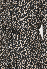 Black dress with beige, white, and brown abstract spots, featuring buttons down the front and a tied fabric belt at the waist.