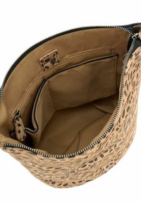 Sac seau beige à motifs avec des taches noires, fermeture éclair, et intérieur beige comportant des poches pour l'organisation et une étiquette de marque.