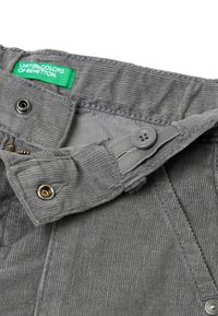 Grijze ribfluwelen broek met een groene label, met een knoopsluiting, ritssluiting en zichtbare stikdetails.