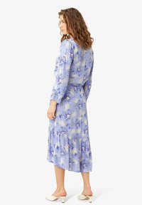 Rochie midi florală în albastru deschis, cu mâneci lungi, detalii pliate, tiv în straturi și modele florale multicolore.
