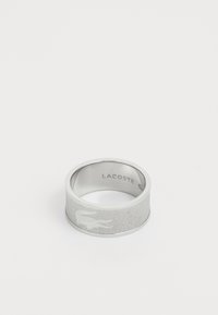 Bague en argent avec une finition mate, dotée d'une surface texturée et du logo Lacoste gravé. Forme ronde avec une large bande.
