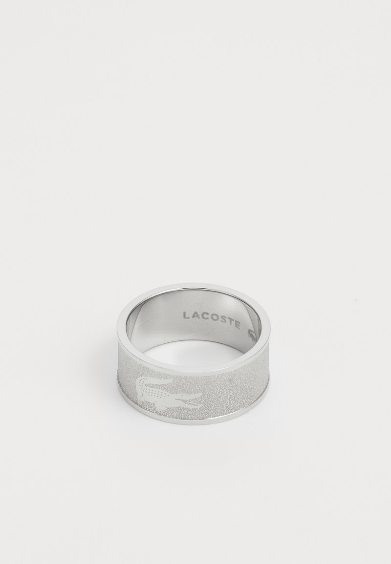 Bague en argent avec une finition mate, dotée d'une surface texturée et du logo Lacoste gravé. Forme ronde avec une large bande.