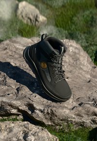 Boot da trekking nero con design high-top, materiale impermeabile, punta rinforzata e suola in gomma testurizzata. Presenta occhielli in metallo e logo.