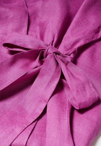 Tissu violet noué en un joli nœud, mettant en valeur la texture et les plis doux du matériau.
