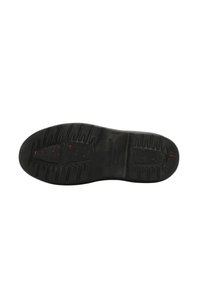 Suela de zapato de goma negra con patrón texturizado y ligeras motas rojas. Presenta una forma redondeada con ranuras para tracción y estabilidad.