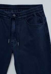Pantalones de chándal azul marino con cinturilla elástica, cordón, bolsillos frontales y extremos de cordón con punta metálica.