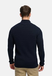 Marineblå kabelstrikket genser med høy krage, strukturert overflate og ribbede mansjetter. Designet for en tett passform med ensfarget stil uten mønstre.