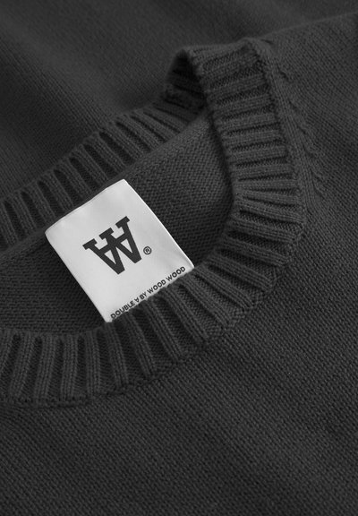 Suéter de punto gris oscuro con un cuello acanalado. Etiqueta blanca con logotipo y el texto "DOUBLE Y BY WOOD WOOD" visible en el escote.