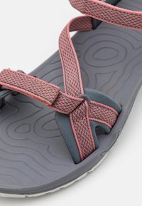 Grå sandal med rosa nätband, utrustad med ett texturerat sulmönster och ett distinkt remdesign för säker passform och bekväm användning.