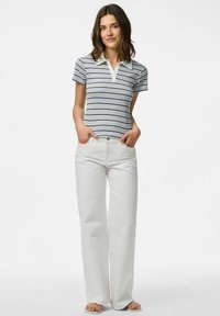 Svītraina polo krekls zilā, baltā un brūnā krāsā ar apkakles kakla izgriezumu, apvienots ar baltām platām biksēm un siksnām sandālēm.