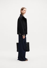 Čierna oversized bunda vyrobená z mäkkého materiálu, skombinovaná s voľnými tmavomodrými nohavicami. Obsahuje jednofarebnú čiernu tašku s textúrou. Jednoduchý, moderný dizajn.