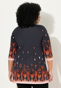 Kurzärmeliges, dunkelblaues Oberteil mit lebhaften orangefarbenen und rosa Mustern am Saum und an den Ärmeln, weich im Griff und mit lockerer Passform.