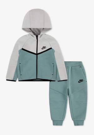 Ensemble de survêtement Nike comprenant une veste à capuche zippée gris clair et vert d'eau, avec des accents noirs, accompagnée de pantalons fuselés assortis en vert d'eau.