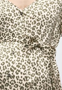 Λευκό φόρεμα με κουμπιά, με λεοπάρ σχέδιο σε σκούρο ελιά πράσινο και ζωνάκι από ύφασμα δεμένο στη μέση.