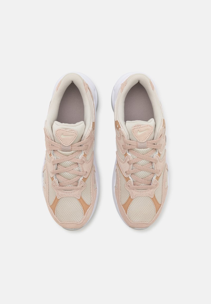 Baskets beige clair avec des panneaux en maille et en daim, dotées d'une surface texturée, d'une semelle blanche et de lacets assortis. Détail de marque minimal visible.