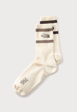 Paar cremefarbener Knöchelsocken mit braunen Streifen, The North Face-Logo und "1966" auf dem Zehenbereich gedruckt.