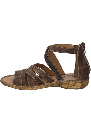 Brown leather sandal with crisscross straps, side zipper, natural textured sole, and beige stitching. Open toe and ankle design.