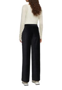 Marineblauwe wijde broek in een zachte, gestructureerde stof, gecombineerd met een lichte, lange mouw top. De outfit heeft een ontspannen silhouet.