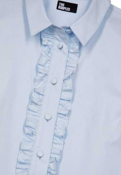 Camisa azul claro de tela suave con un frente fruncido y un cuello redondeado, con botones cubiertos de tela a juego.