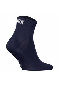 Navy blue ankle sock made of stretchy material, featuring a ribbed cuff and white logo detail along the side. Smooth texture.