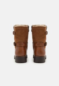 Braune Wildleder- und strukturiertes Lederstiefel mit Schafslederfutter, zwei Riemenakzenten und einer stabilen schwarzen Sohle. Die Rückansicht zeigt die Reißverschlüsse.
