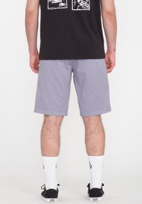 Grå shorts lavet af letvægtsstof, med en afslappet pasform og manchetter i kanten. Båret med sorte sko og hvide mønstrede sokker.