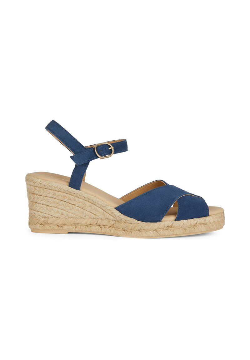 Sandalo con zeppa blu in suede, con punta aperta e cinturini incrociati. Presenta un cinturino alla caviglia con una fibbia dorata e una piattaforma avvolta in juta testurizzata.