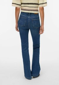 Lainelised sinise teksariidest püksid keskmise kõrgusega vöökohaga, tagataskudega ja kergelt heledamaks kulunud äärega. Materjal tundub vastupidav ja klassikaline.