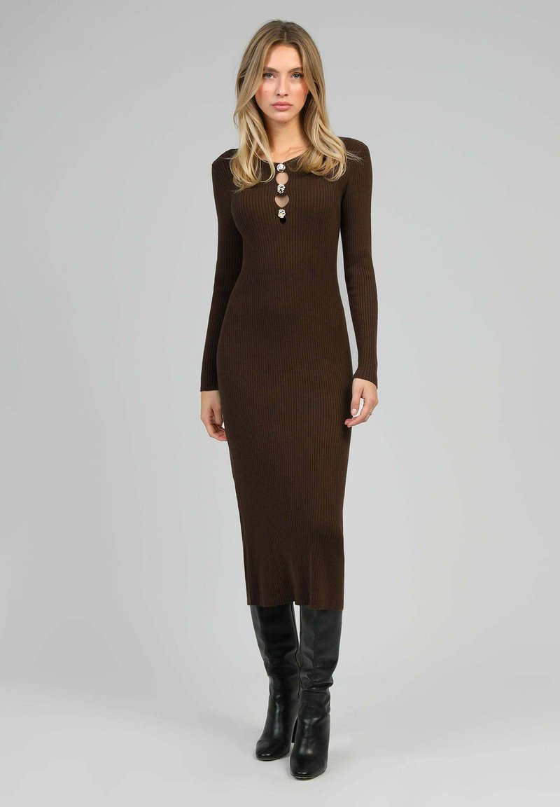 Robe longue en tricot côtelé marron à manches longues avec un col à boutons, associée à des bottes noires à talons hauts jusqu'aux genoux. Texture lisse, silhouette ajustée.