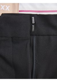 Černé látkové kalhoty se zapínáním na zip a dvěma obdélníkovými kovovými akcenty na pase. Hladká textura a přizpůsobený design.