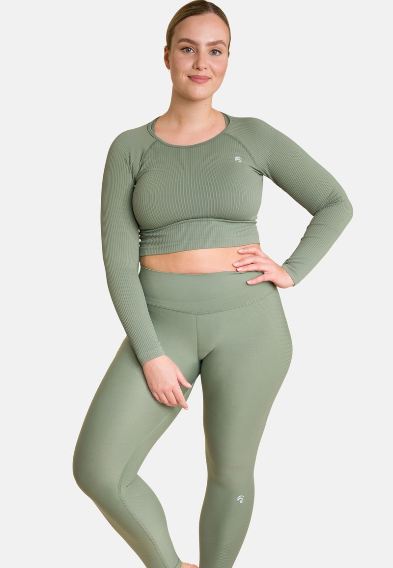 Rippierter langärmliger Cropped-Top und hochgeschnittene Leggings in Salbeigrün, mit einem figurbetonten Design und einem kleinen Logo an der Seite der Leggings.