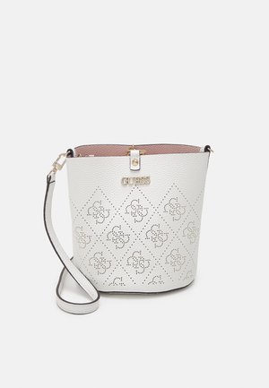 Hvid tekstureret læder bucket taske med perforeret blomster mønster, gyldent GUESS-logo og justerbar rem på hvid baggrund.