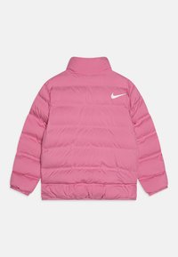 Giacca imbottita rosa con colletto alto, caratterizzata da un trapuntato orizzontale e un logo Nike bianco sulla parte superiore della schiena. Texture liscia.