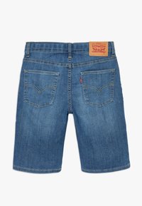 Shorts de mezclilla en azul medio con corte limpio. Presenta dos bolsillos traseros, costuras en contraste y un parche de cuero de la marca en la cintura.