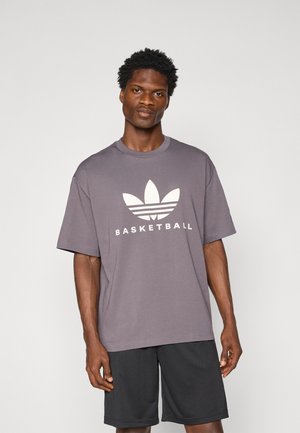 Gray cotton t-shirt featuring a large white Adidas logo with three leaves and the word "BASKETBALL" below. Short sleeves and relaxed fit.