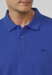 Koninklijk blauwe polo met een gestructureerde stof, met een klassieke kraag, een drieknoopsluiting en een geborduurd s.Oliver-logo.