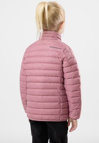 Lyserød pufferjakke med horisontalt quiltet design, høj krave og sort "SWEDEMOUNT" logo på ryggen. Båret med sorte bukser.