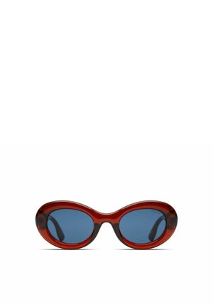 Lunettes de soleil rouges surdimensionnées avec des montures ovales et des verres bleus. La monture a une finition brillante, avec un subtil motif marbré sur les bords.