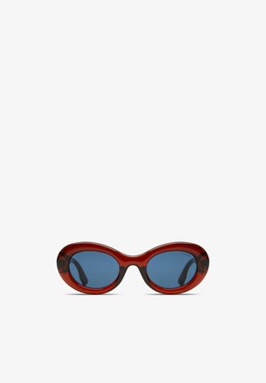 Red oversized sunglasses with oval frames and blue lenses. The frame has a glossy finish, featuring a subtle marbled pattern on the edges.