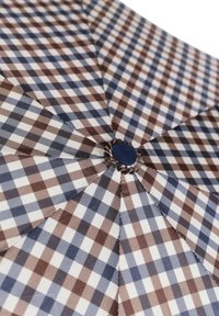 Ombrello a quadri con motivi blu, marroni e bianchi. I pannelli di tessuto convergono in un bottone centrale, mostrando un motivo strutturato.