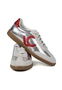 Zapatillas plateadas con acentos de purpurina roja y un logo, que presentan una mezcla de materiales suaves y texturizados, y una suela de goma marrón.