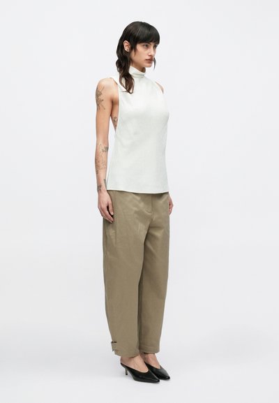 Kreemjas varrukateta topp kõrge kaelusega, koos lahtiste harki pükstega ja mustade teravate kontsadega, millel on peen tekstuur ja lõdvestunud istuvus.