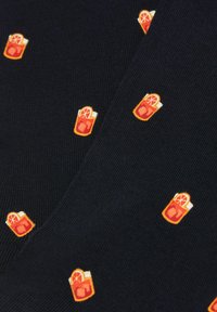 Mørkeblå stof med et gentagent mønster af broderede orange cocktailglas med en skive, detaljeret i orange, gul og hvid.