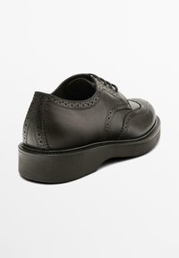 Schwarze Leder-Brogues mit perforierten Details, runder Zehenpartie und einer dicken, stabilen Sohle. Verfügt über ein klassisches Schnürdesign.