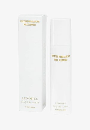 Botella blanca y caja para "Prestige Rebalancing Milk Cleanser", con texto en dorado. La botella tiene una textura suave y una forma redondeada.