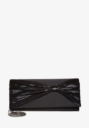Pochette noire avec un détail nœud pailleté en sequins et une bandoulière chaîne argentée, conçue pour une tenue de soirée.